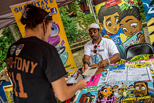 Marcus Williams (right) hands Candice Meyer a sketch of her cat during the 5 Arts Fest in the Little Five Points neighborhood of Atlanta on Saturday, September 12, 2015.