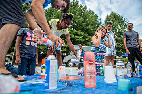 Ricci DeJesus (left), Yahkirah Manggium, and Kaitlin Green spray paint old records as they create art during the 5 Arts Fest in the Little Five Points neighborhood of Atlanta on Saturday, September 12, 2015.