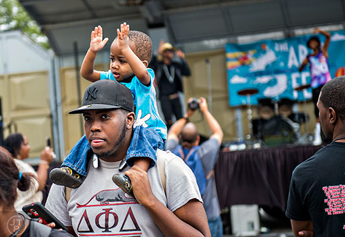Cortez Thornton claps along to the performance on the main stage as he rides on Raashad Forney's shoulders during the 5 Arts Fest in the Little Five Points neighborhood of Atlanta on Saturday, September 12, 2015. 