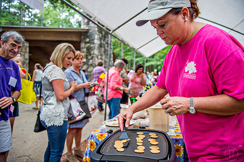 Sheree Elliott (right) flips tiny pancakes as she makes samples for people to taste during the Yellow Daisy Festival at Stone Mountain Park on Saturday, September 12, 2015. 