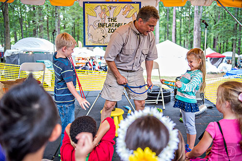 Adam Komesar (center) gets help from Pierce Lawson (left) and Haley Carpenter as he entertains children during the Yellow Daisy Festival at Stone Mountain Park on Saturday, September 12, 2015.