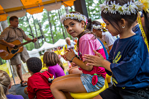 Lydia Cothran (center) claps along as Adam Komesar performs during the Yellow Daisy Festival at Stone Mountain Park on Saturday, September 12, 2015. 