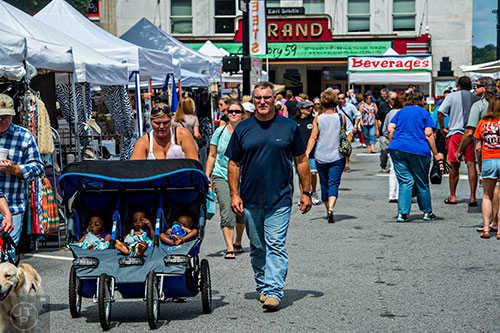 Michael Stephens (right) walks with his wife Dinah as she pushes their triplets Mia, Zoe and Sy in a stroller during the Marietta StreetFest in the historic downtown square on Saturday, September 19, 2015.  