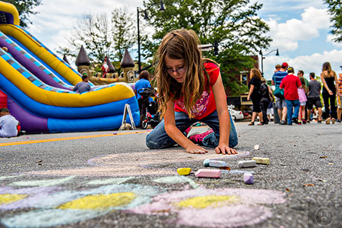 Emma Tully draws on the street with chalk during the Marietta StreetFest in the historic downtown square on Saturday, September 19, 2015.  