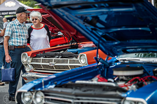 Jimmy Merrill (left) and Ann Pratt walk down a row of classic muscle cars during the Marietta StreetFest in the historic downtown square on Saturday, September 19, 2015.  