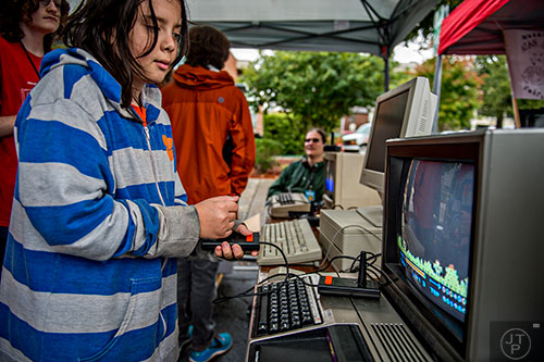 Ashton Christo (left) plays a game on an old Texas Instruments TI-99 console during the Atlanta Maker Faire in Decatur on Saturday, October 3, 2015. 