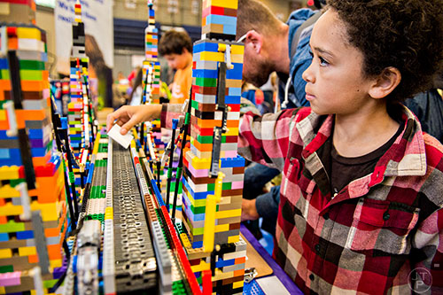 John Currie (right) sends a note down a conveyor belt made from LEGOs during the Atlanta Maker Faire in Decatur on Saturday, October 3, 2015.