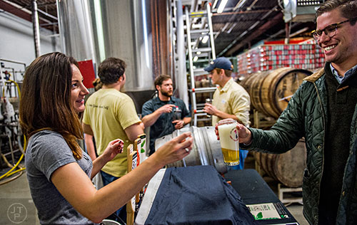 Riley O'Connor (left) hands a beer to Michael Dauterman during the Second Self Beer Company's one year anniversary celebration in Atlanta on Saturday, October 3, 2015. 