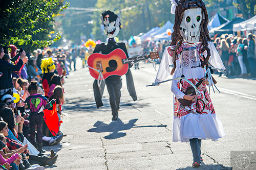 Sandy Nichols (right) plays the guitar as she walks up the street during the Little Five Points Halloween Parade in Atlanta on Saturday, October 17, 2015. 