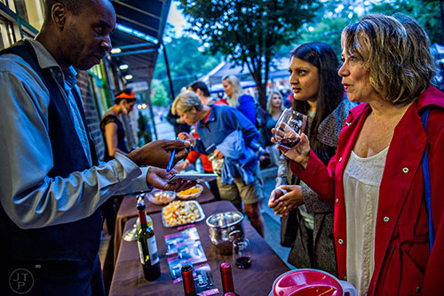 Kevin Wilson (left) marks off the wine that Priya Desai and Donna Janney try during the Kirkwood Wine Stroll on Friday. 