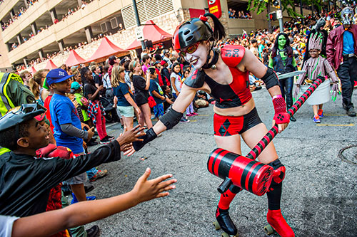 Ezra Kyiamah (left) reaches for a high five from Deirdre Kondrick as she rollerskates by during the annual DragonCon Parade in Atlanta on Saturday, September 5, 2015.