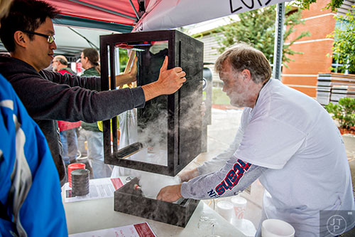 Phillip Wu (left) helps Alan Davies with his vortex machine as he sets in a tub of dry ice during the Atlanta Maker Faire in Decatur on Saturday.