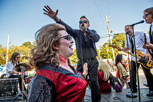 Cory Poucher (center) reaches out over his wife Candice's head as he performs on the back of a float during the Little Five Points Halloween Parade on Saturday, October 17, 2015.