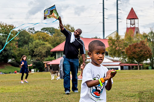 Anthony Parker Jr. (center) runs as his father Anthony Sr. holds his kite up to catch the wind during the Atlanta World Kite Festival at Piedmont Park on Saturday, October 24, 2015. 