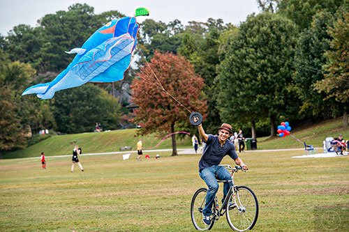 Parker Bugg rides his bike as he flies a kite during the Atlanta World Kite Festival at Piedmont Park on Saturday, October 24, 2015.