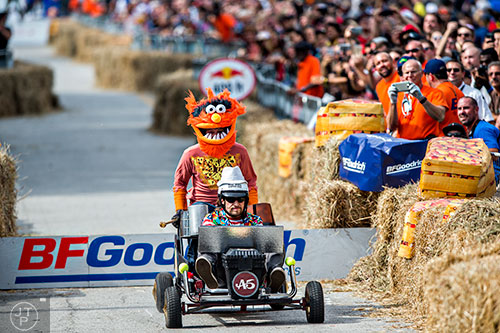 Dressed as Animal from the Muppets, Pete Massey holds on to the back of the car after his driver clears the jump during the Red Bull Soap Box Derby in Atlanta on Saturday, October 24, 2015.