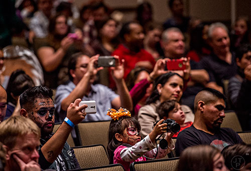 Leidie Denisse Canizalez-Perez (center) takes photos of the Atlanta Symphony Orchestra as they perform during the Dia De Muertos, or Day of the Dead, Festival at the Atlanta History Center on Sunday, November 1, 2015. 