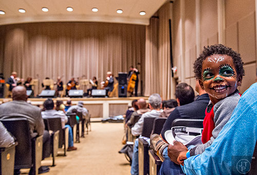 Evan Wright smiles as he looks back at his mother while members of the Atlanta Symphony Orchestra perform during the Dia De Muertos, or Day of the Dead, Festival at the Atlanta History Center on Sunday, November 1, 2015. 