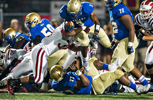McEachern's Tyler Simmons (3) leaps over teammate Andrew Tarver (77) as he is tackled by Hillgrove's Cameron Tew (left) on Friday, November 6, 2015.