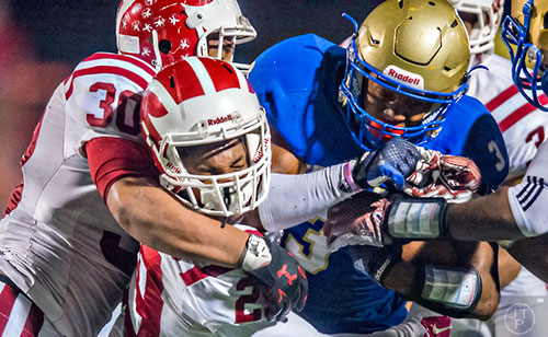 McEachern's Tyler Simmons (3) keeps the ball safe as he is tackled by Hillgrove's Jared Pryor (29) and Cameron Tew (30) on Friday, November 6, 2015. 