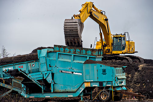 An excavator moves piles of dirt and debris into a mulching machine at the Seminole Road Landfill on Wednesday, November 4, 2015. 