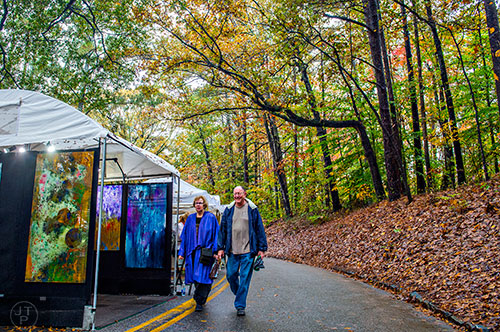 Sharon Stein (left) walks past artist booths with Robert Dopp during the Chastain Park Arts Festival on Saturday, November 7, 2015. 
