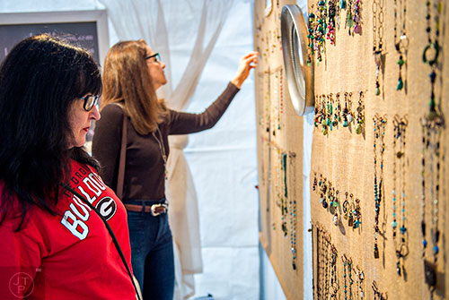 Susan Rifkin (left) looks at jewelry designed by Laura Lambert during the Chastain Park Arts Festival on Saturday, November 7, 2015. 