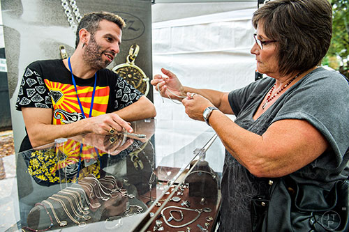 Hanan Ingel (left) talks with Terri Morgan as she tries to decide which necklace to purchase during the Chastain Park Arts Festival on Saturday, November 7, 2015. 