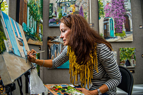 Julie Rogers paints as she waits for people to stop by her booth during the Chastain Park Arts Festival on Saturday, November 7, 2015. 