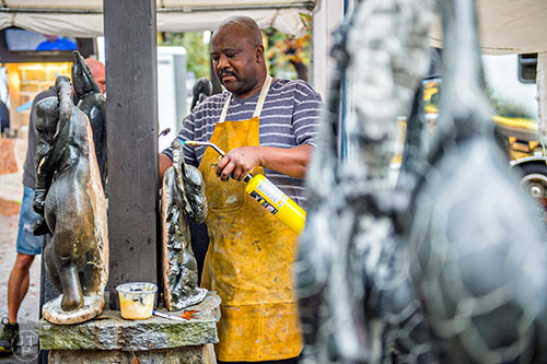 Peter Rujuwa uses a torch to make adjustments to one of his sculptures during the Chastain Park Arts Festival on Saturday, November 7, 2015. 