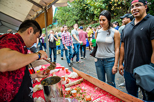 Jared Palatchi (right) and Rachel Kleiman wait for Simon Beats to pour chili in containers for them to taste during the Cabbagetown Chomp & Stomp in Atlanta on Saturday, November 7, 2015.