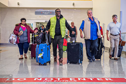 Will Bogle (center left) and his wife Rebecca Hill-Bogle (left) exit customs in the international terminal of the Hartfield Jackson International Airport in Atlanta on Saturday, November 14, 2015. 
