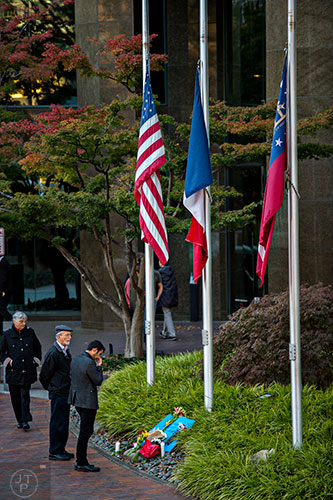 Mary Moon (left) walks towards her husband Bill and another man as they stand in front of a memorial outside of the Consulate General of France's offices at the Buckhead Tower at Lenox Square in Atlanta on Saturday, November 14, 2015. 