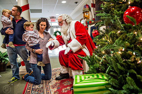 Leslie Fisher (center) holds her son Lawson as she and her husband Rob coax their son and his brother Jackson to have a photo taken with Santa during the Dunwoody United Methodist Church Holiday Festival on Saturday, November 14, 2015. 