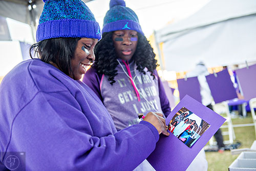 Ayanna Muhammad (left) and her sister Halimah work to hang a picture of their father before the start of the PurpleStride Atlanta 5k at Centennial Olympic Park in Atlanta on Saturday, November 14, 2015. 