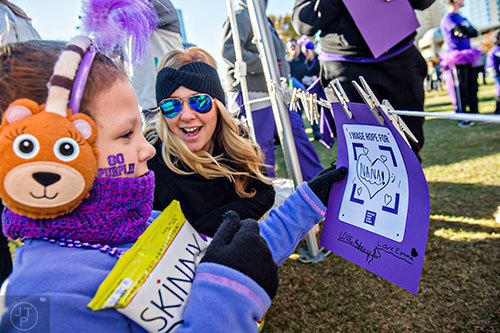 Aubrey Carros (left) and her mother Tonya hang a tribute to Aubrey's grandmother before the start of the PurpleStride Atlanta 5k at Centennial Olympic Park in Atlanta on Saturday, November 14, 2015.  
