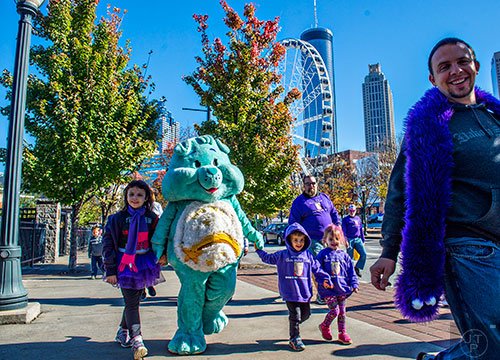 Dressed as a Care Bear, Veronica Bramlett (center) holds hands with her step daughter Emily (left), Alex Payne and his sister Jenna as they walk in the PurpleStride Atlanta 5k at Centennial Olympic Park in Atlanta on Saturday, November 14, 2015. 