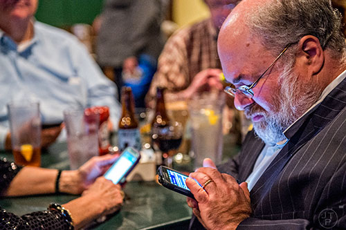 Dave Markus checks poll results on his phone during the Dekalb Strong viewing party at Melton's app & tap on Tuesday.