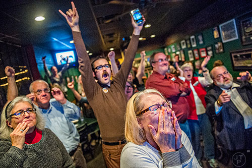 Melissa Montgomery (center) and Jon Fidler react as they watch poll results during the Dekalb Strong viewing party at Melton's app & tap on Tuesday.