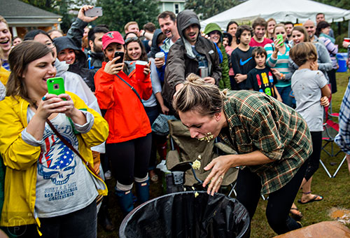 Anna Kristine Roth (right) spits out cole slaw into a trash can after competing in the cole slaw eating contest during the Cabbagetown Chomp & Stomp in Atlanta on Saturday, November 7, 2015.