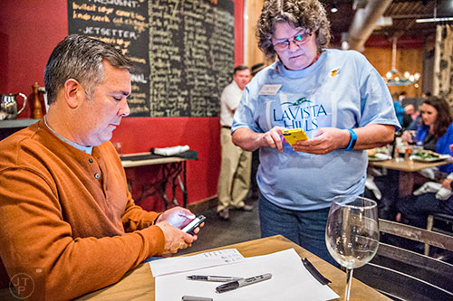 Matt Slappey (left) and Amy Parker check their phones for poll results during the Lavista Hills viewing party at Sprig on Tuesday.  