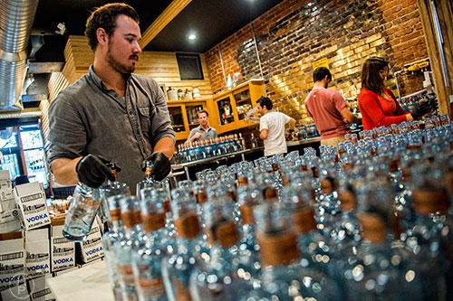 William Broder moves empty bottles from the staging area to the filling station during bottling day at Old Fourth Distillery in Atlanta.