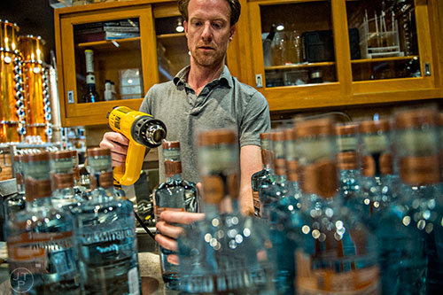 Jeff Moore uses a heat gun to seal bottles of vodka during bottling day at Old Fourth Distillery in Atlanta.