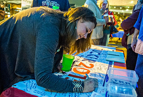 Sonja Szubski signs the Tucker 2015 sign during the election night party on Main St. on Tuesday.