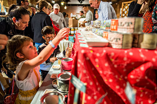 Gratia Custred (left) reaches for a tasting stick at the Beautiful Briny Sea booth during the Indie Craft Experience's Holiday Shopping Spectacular at the Georgia Freight Depot in Atlanta on Saturday, November 21, 2015. 
