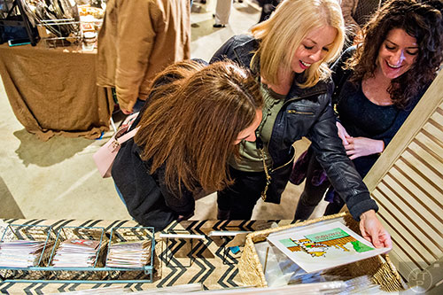 Meghan Shakar (right), Allison Goreham and Allison Katz look at a painting by Heather Lund during the Indie Craft Experience's Holiday Shopping Spectacular at the Georgia Freight Depot in Atlanta on Saturday, November 21, 2015. 