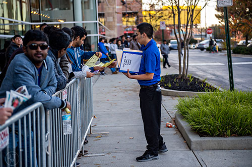 Marlon Castillo (right) hands doorbuster sales tickets to Ashwin Sakhardande as he stands in line outside of Best Buy Perimeter in Atlanta before the store opens for Gray Thursday on Thanksgiving night, Thursday, November 26, 2015. 