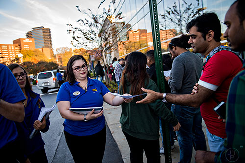 Mia Toro (center) hands a store map to Ameet Thakkar as he stands in line outside of Best Buy Perimeter in Atlanta before the store opens for Gray Thursday on Thanksgiving night, Thursday, November 26, 2015. 