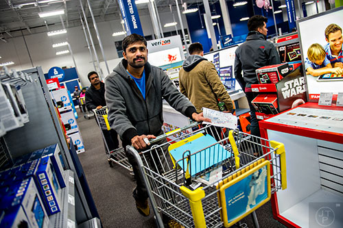 Naveen Kumar (center) pushes his cart through the aisles inside Best Buy Perimeter in Atlanta for Gray Thursday on Thanksgiving night, Thursday, November 26, 2015. 