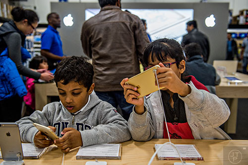 Raghav Bajaj (left) and his sister Ridhima play with iPhones as their father shops inside Best Buy Perimeter in Atlanta during Gray Thursday on Thanksgiving night, Thursday, November 26, 2015. 